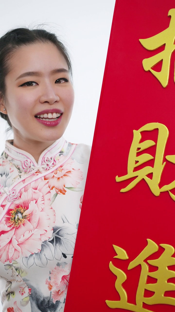 中国/亚洲妇女穿着旗袍，递上大的红色中国招牌，表示新年快乐，富裕，幸福和幸运视频下载