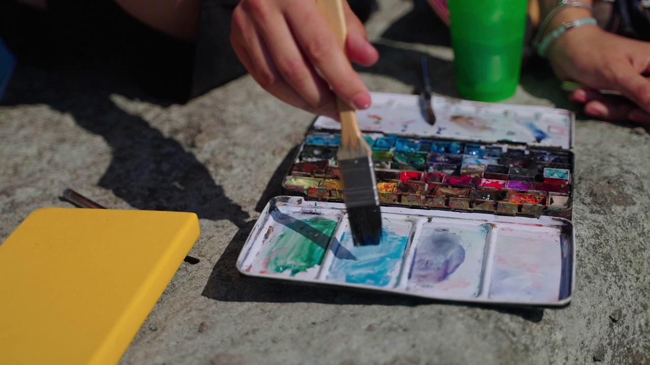一位艺术家正在用水彩画画画，用毛笔涂上蓝色视频素材