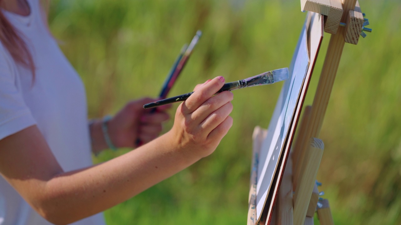 女艺术家用蓝色颜料画着山水画、画架特写视频素材