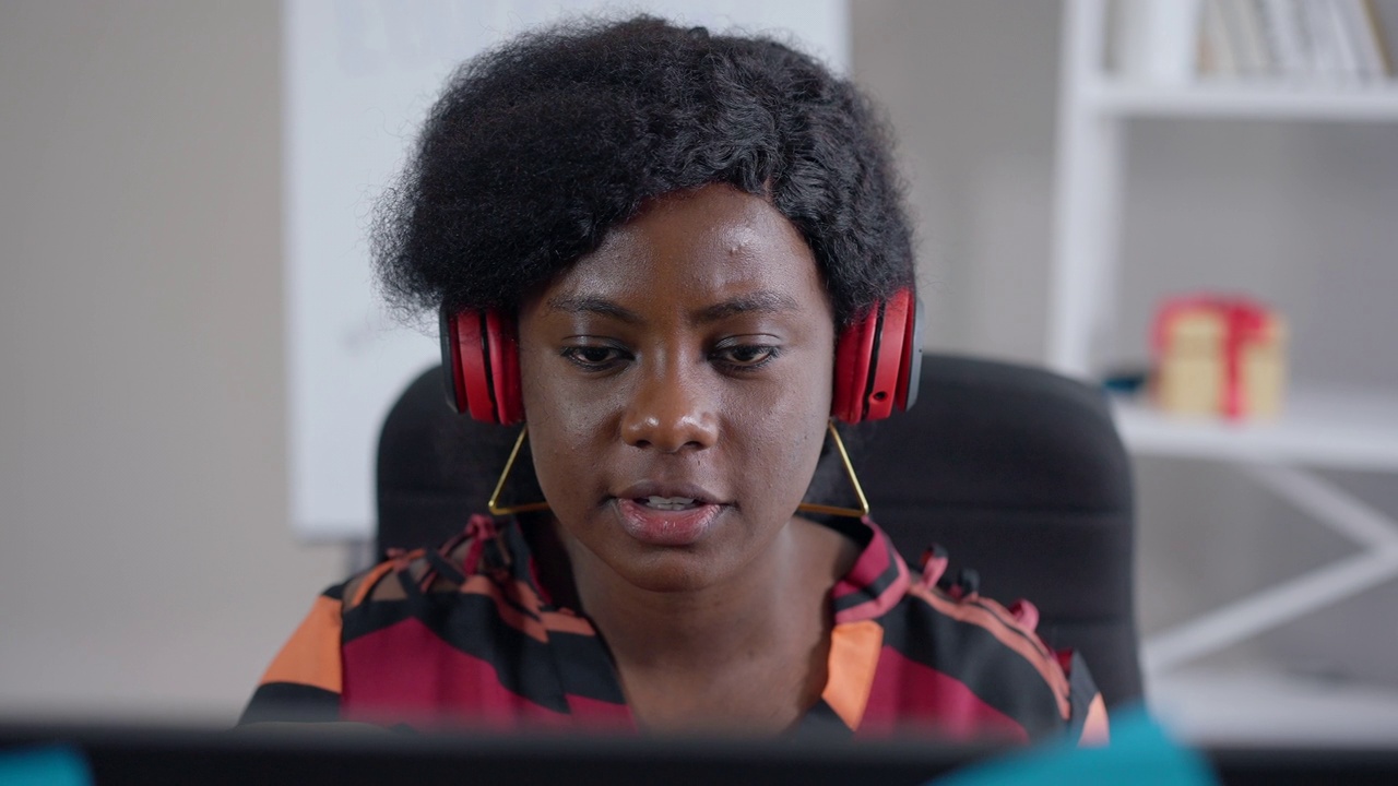 正面观点积极的非裔美国自由职业者在慢动作谈话，看着电脑显示器上的视频聊天。特写肖像微笑自信的女人头脑风暴在线。视频素材
