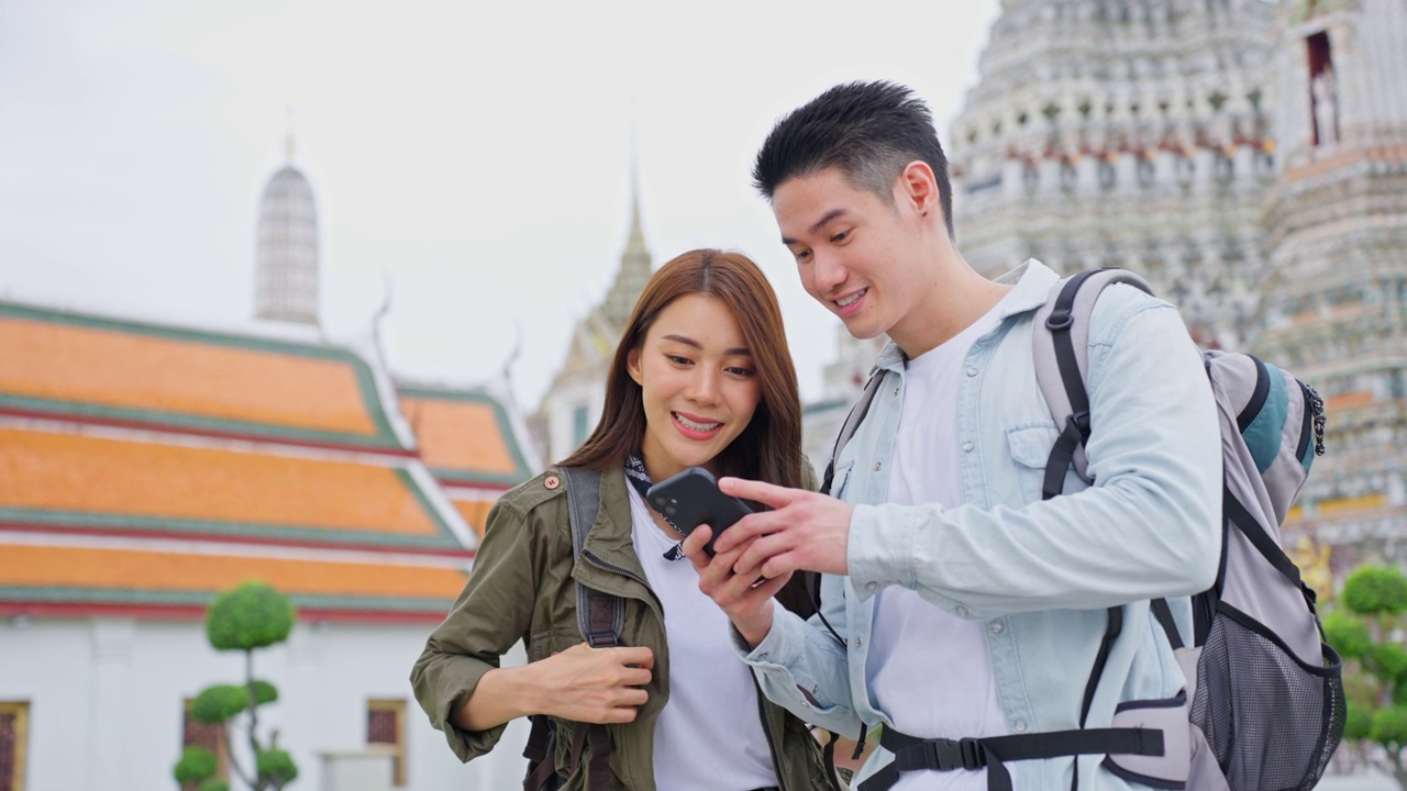 亚洲情侣在这个城市度蜜月。新婚男女背包客用手机寻找目的地，一起享受度假的时光。视频购买