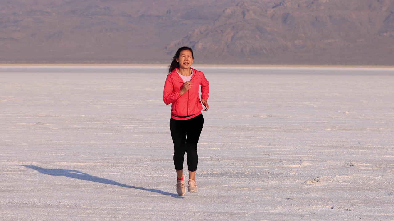 一个亚洲妇女慢跑穿过博纳维尔盐滩视频下载