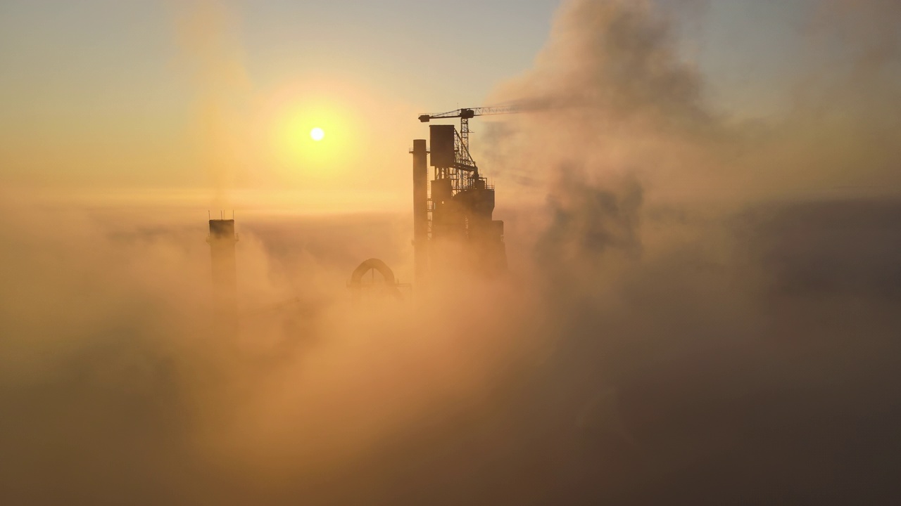 鸟瞰图水泥厂与高混凝土厂房结构和塔吊在工业制造现场雾天晚上。生产和全球产业理念视频下载