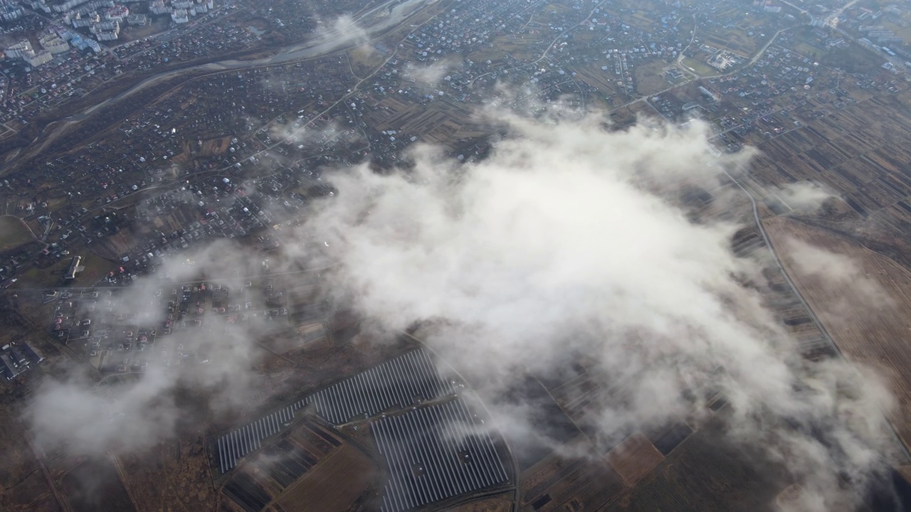 高空鸟瞰图，远处的城市被暴雨前形成的蓬松的积云所覆盖。飞机角度多云的景观视频素材