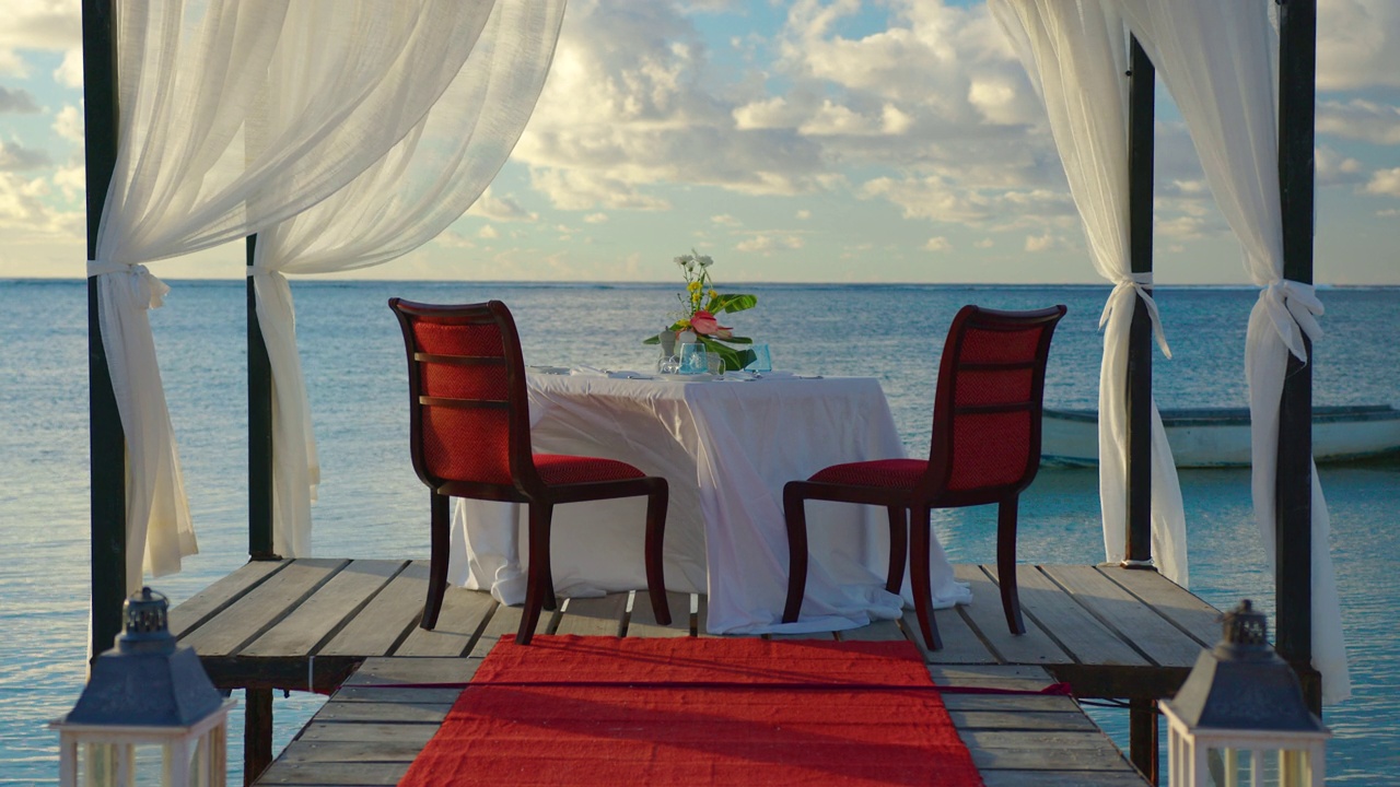 浪漫的晚餐会为两人在夕阳下的海滩上美丽的云彩背景视频下载