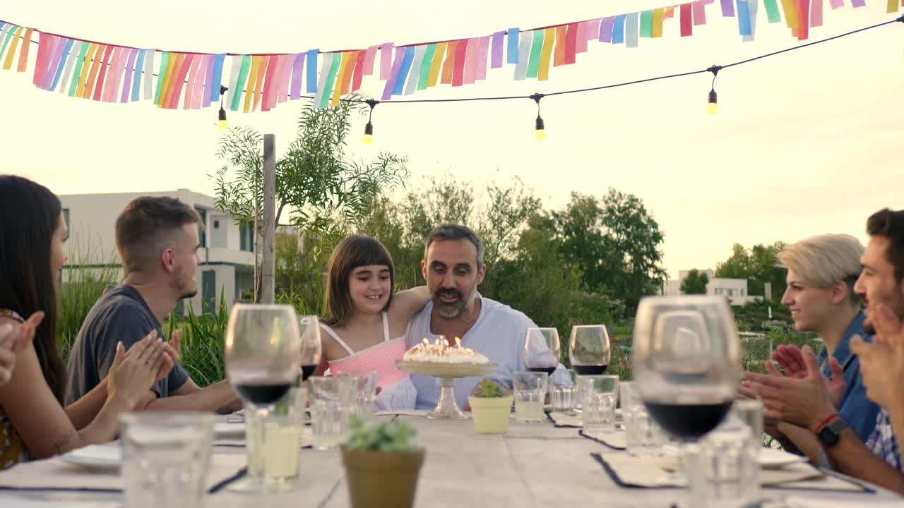 微笑的男人和女儿吹生日蛋糕视频素材