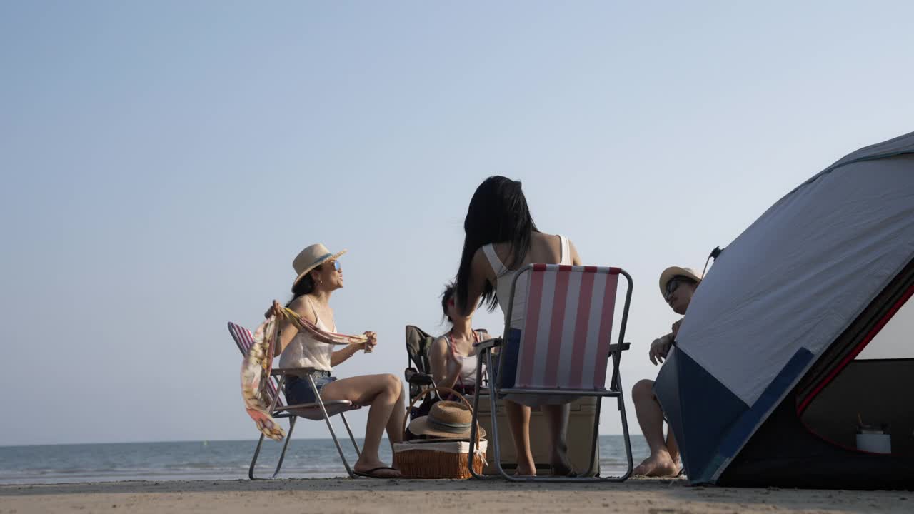 一群亚洲朋友在海滩上野营度假。视频素材