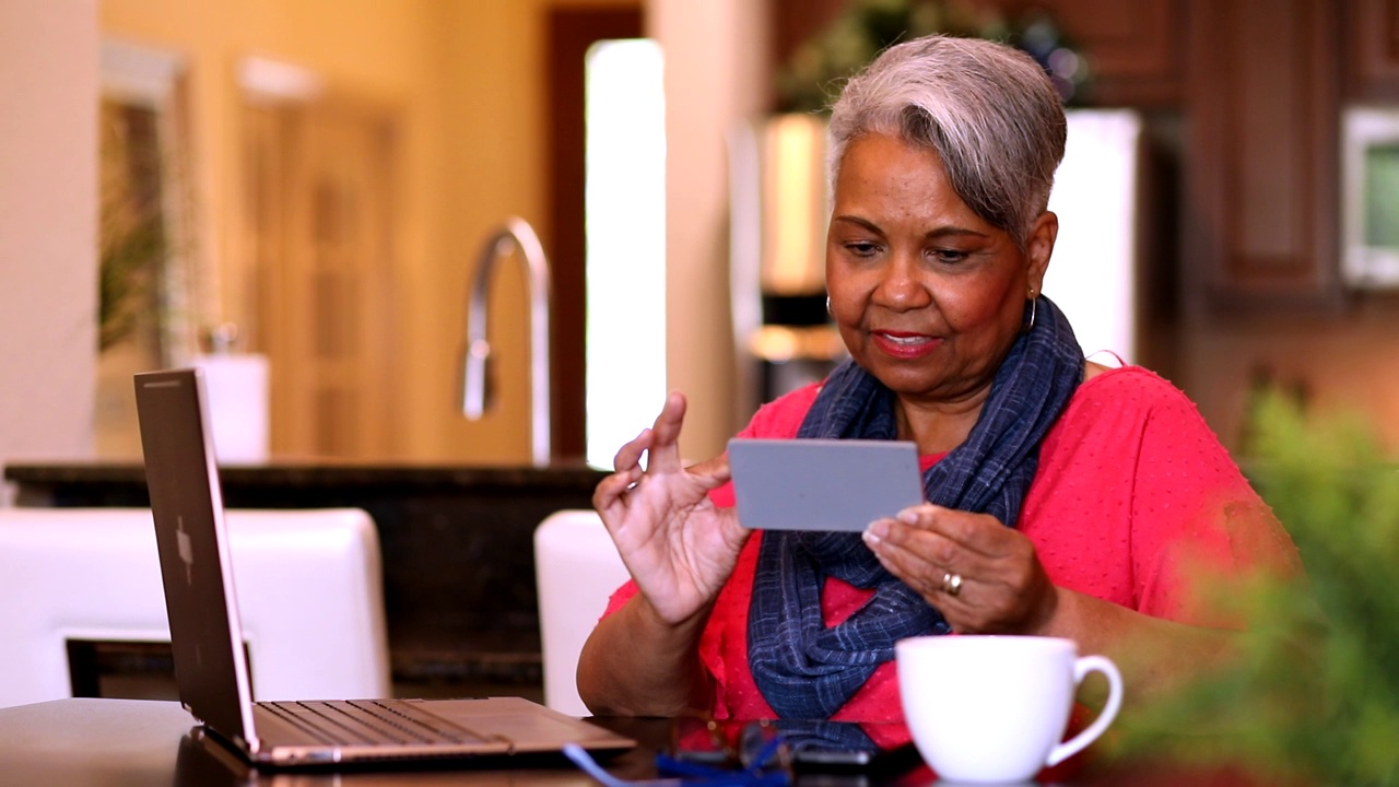 老年女性在家使用手机和笔记本电脑。视频下载