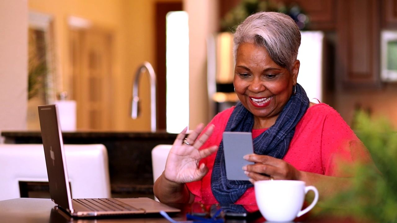 老年女性在家使用手机和笔记本电脑。视频下载