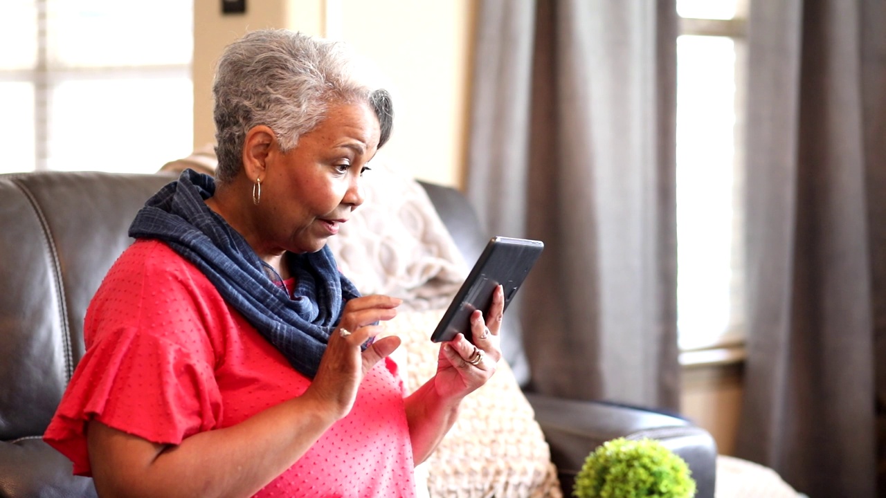 老年女性在家使用数码平板电脑。视频下载