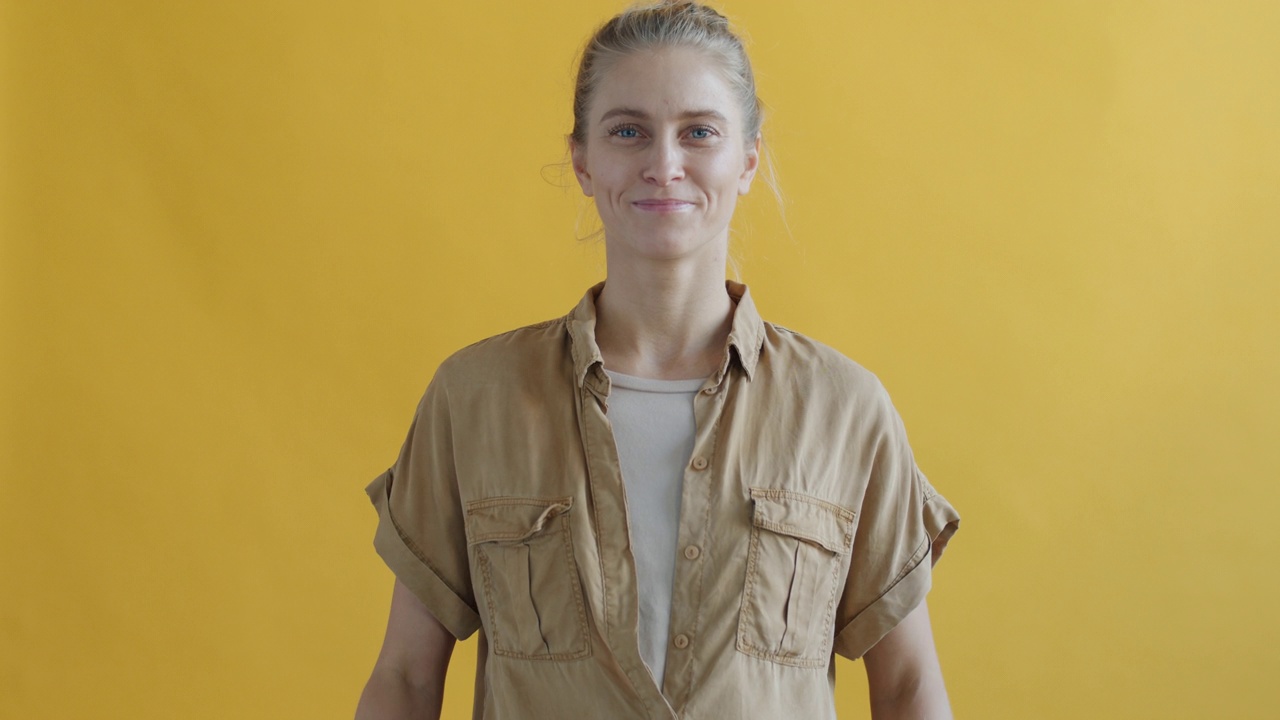 女性活动家的肖像，拿着拒绝塑料的标志，在黄色的背景上微笑视频下载