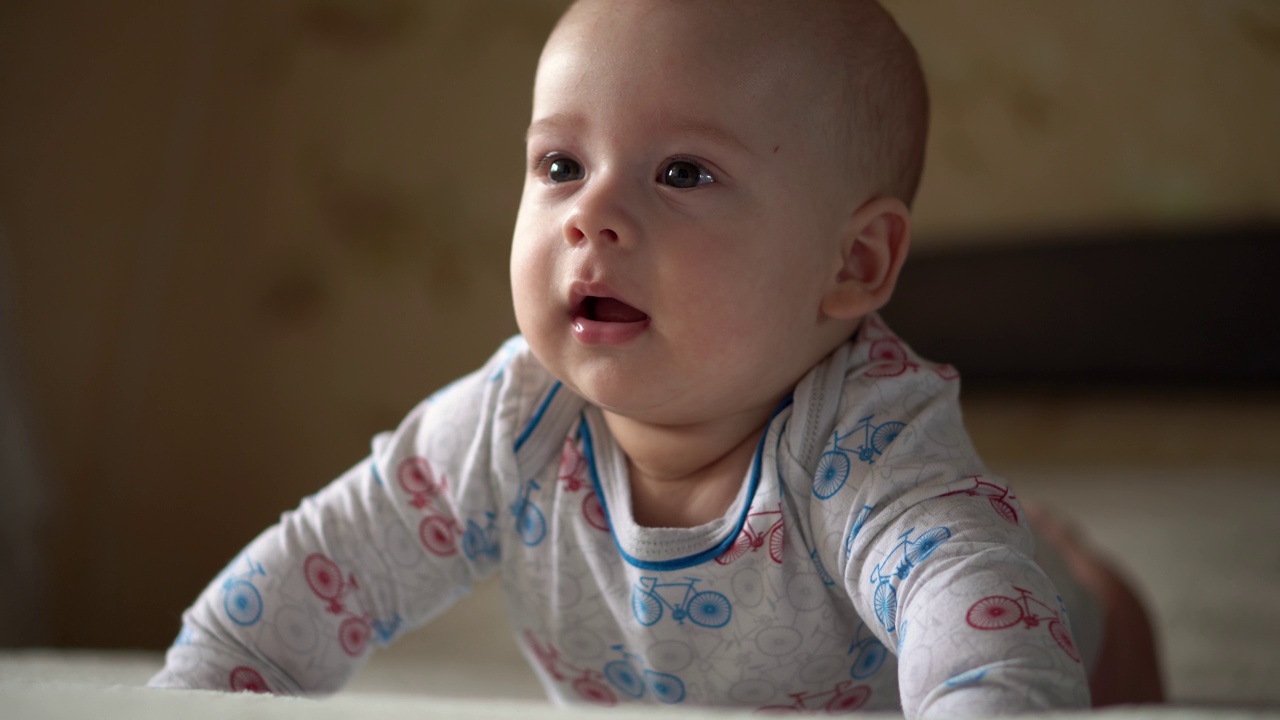 新生兒活躍的嬰兒可愛的微笑的沒有牙齒的臉肖像早期在胃發育的脖子控制。5個月的孩子在白色的床上看著相機。嬰兒，分娩，父母，開始概念視頻素材