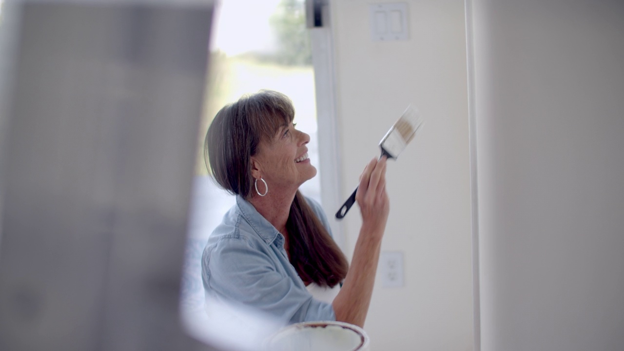 一个成熟的女人正在粉刷她的家视频素材