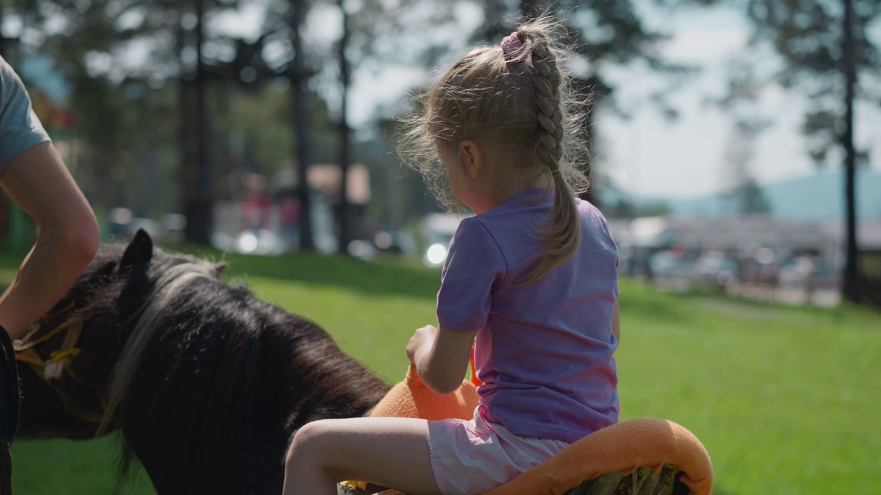 小孩和教练骑着小马沿着城市花园视频下载