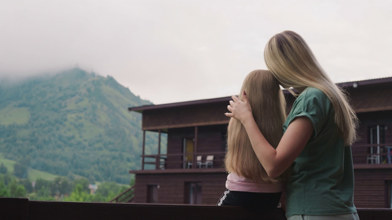慈祥的母亲在生态酒店的阳台上拥抱着她的小女儿视频下载
