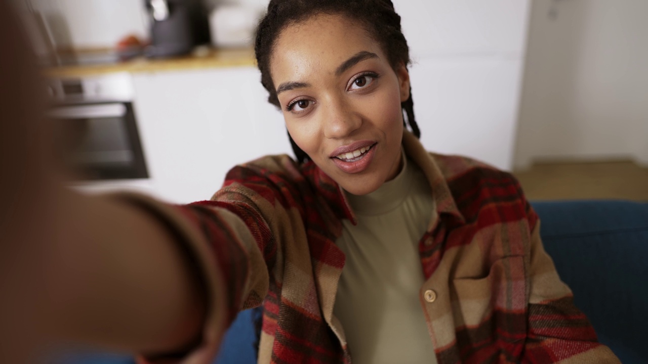 视角拍摄的黑人女孩微笑着自拍，摆姿势看着相机独自在家视频下载