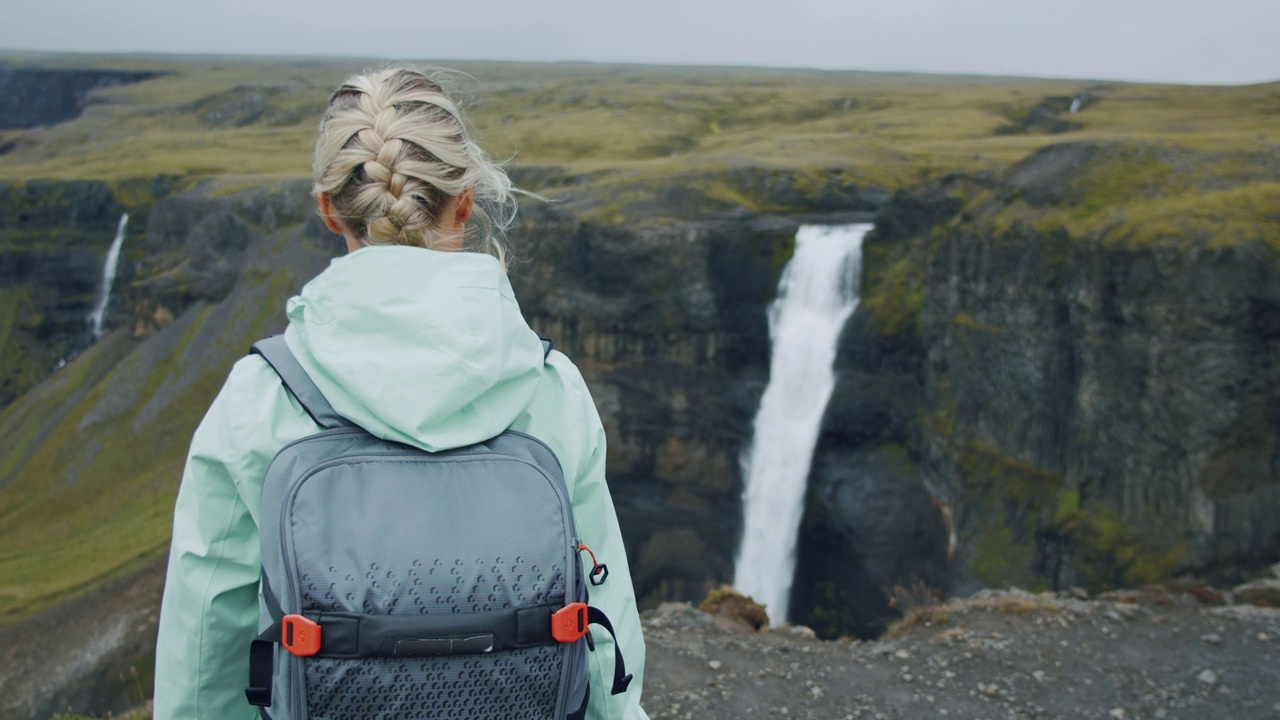 一名女子背着背包走向冰岛高地的海弗斯瀑布视频下载