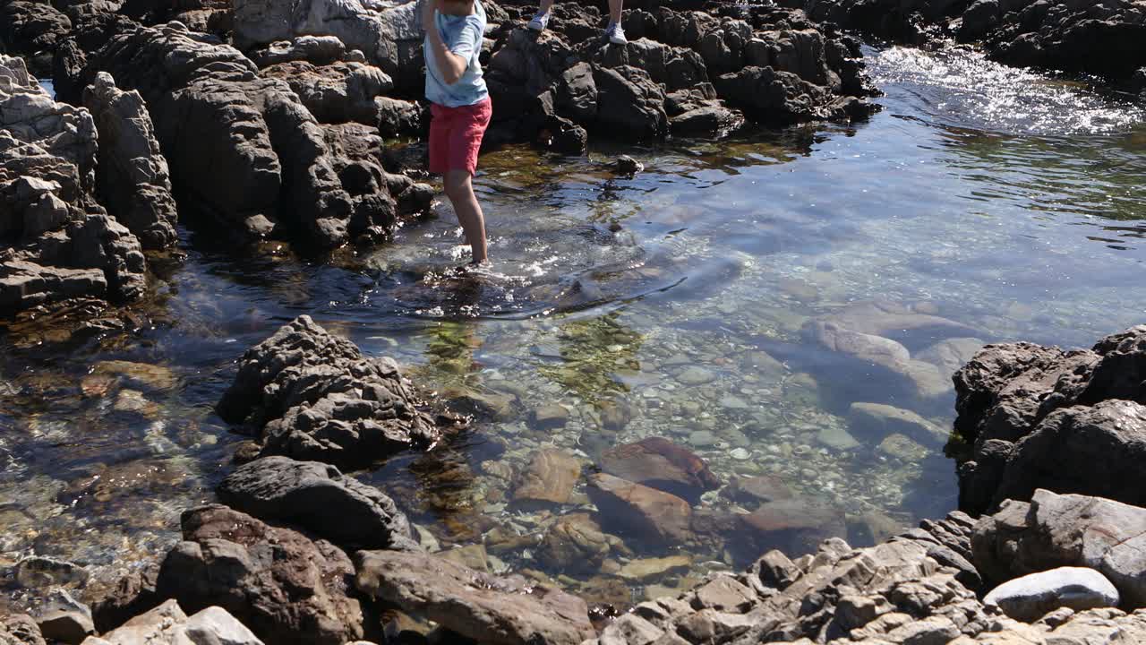 十几岁的女孩和弟弟探索岩石海岸线视频素材
