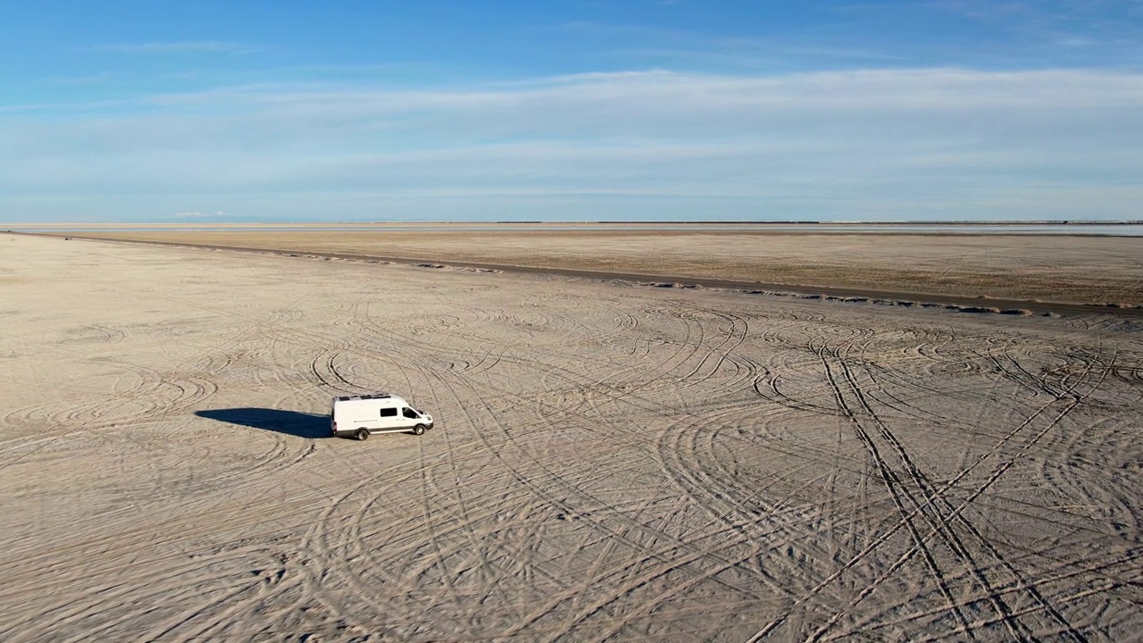 无人机视图改装的短跑露营车行驶在中午的博纳维尔盐滩中部视频下载