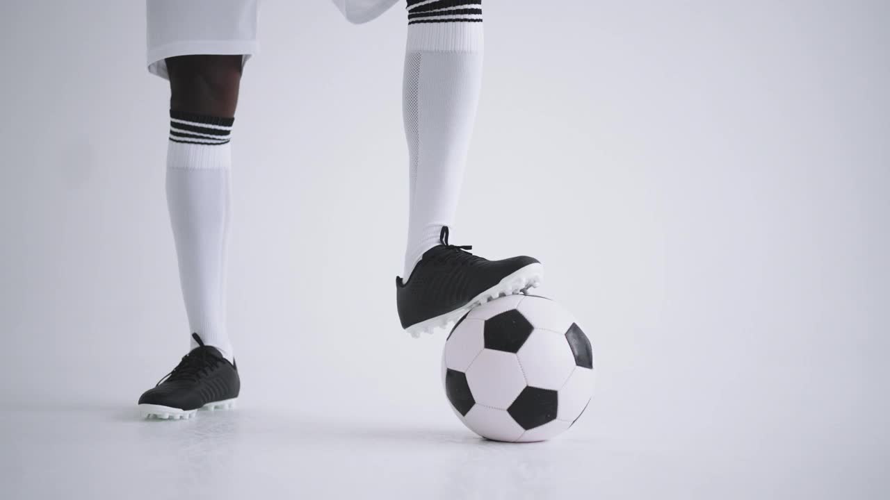 黑人足球运动员在白色背景的工作室与球摆姿势，肖像的前锋视频下载