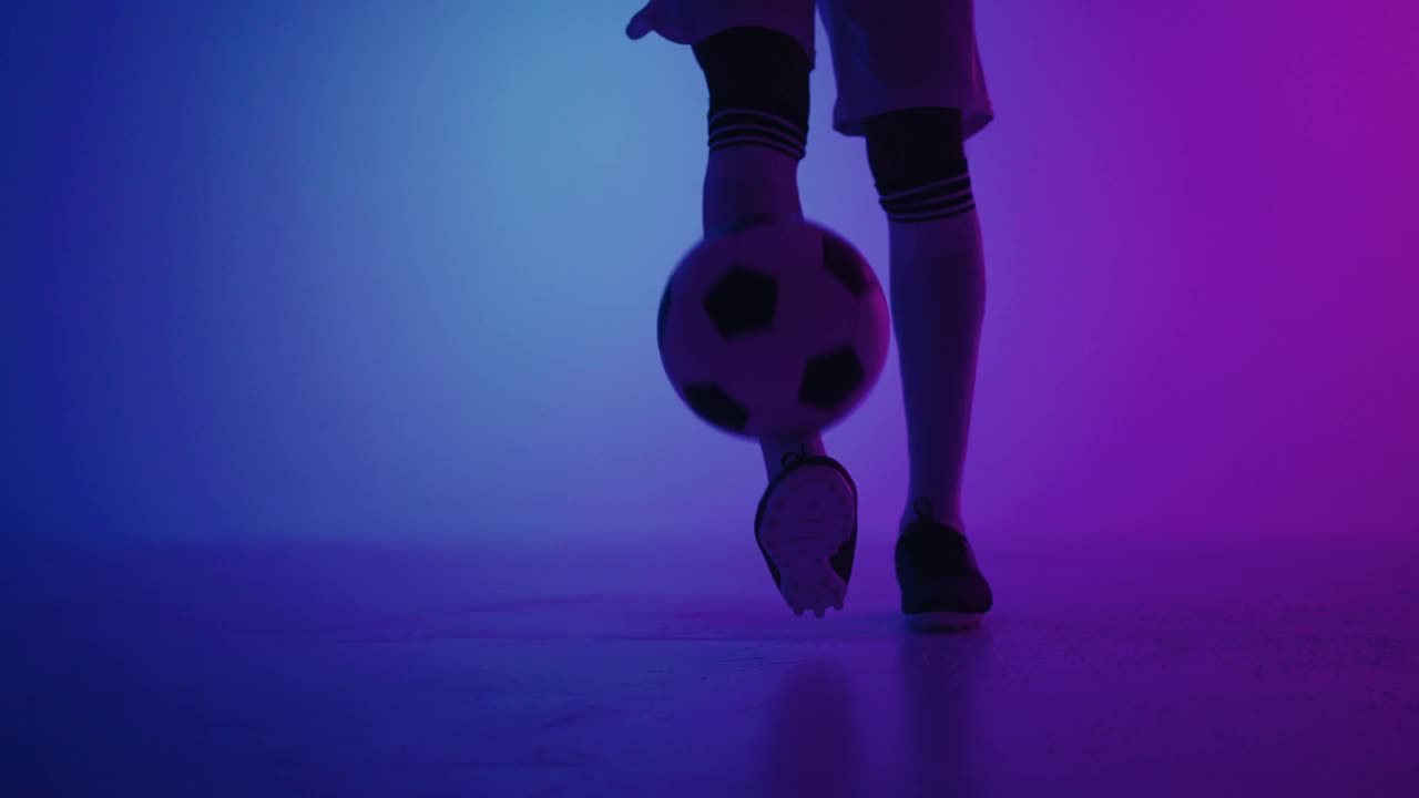 在画室里，足球运动员正在用蓝色和紫色两种颜色的球玩球，脚部特写视频素材