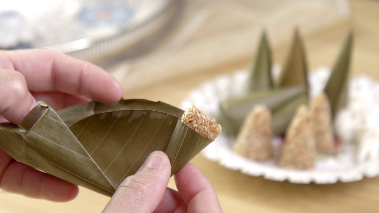 女人用手打开金字塔形泰国甜点的香蕉叶包裹。传统食品为中国新年、节日、仪式的概念。视频下载