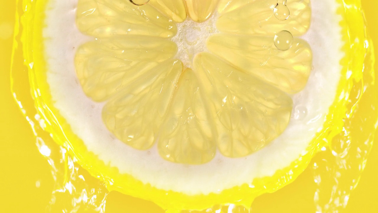 柠檬片从黄色背景的顶部泼水慢动作视频素材