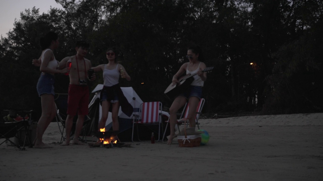 一群亚洲朋友在海滩上野营度假。视频素材