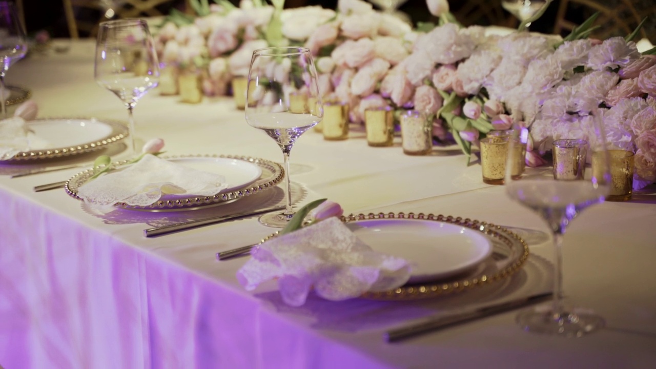 餐厅餐桌上的婚礼插花和玫瑰。美丽的婚礼服务，玻璃和盘子在餐厅视频下载