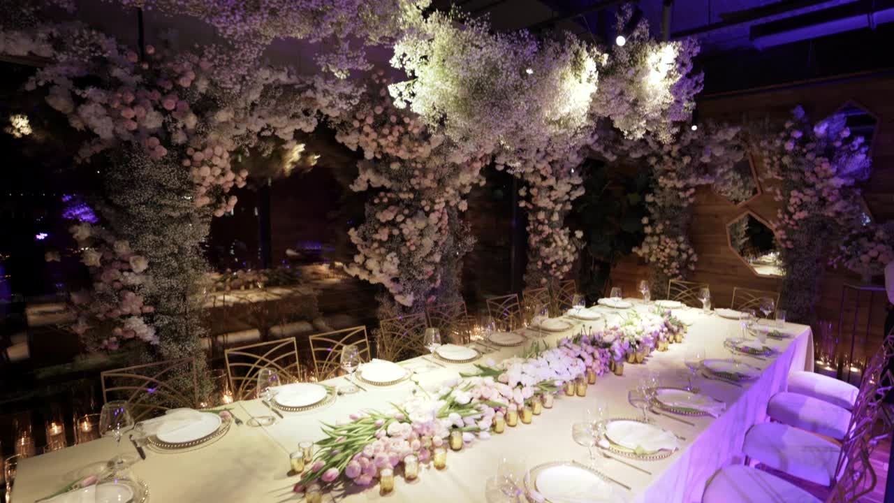 餐厅大厅装饰着婚礼用的鲜花。餐厅里为婚礼准备的桌椅。空酒杯和盘子。有节日气氛的好地方视频下载