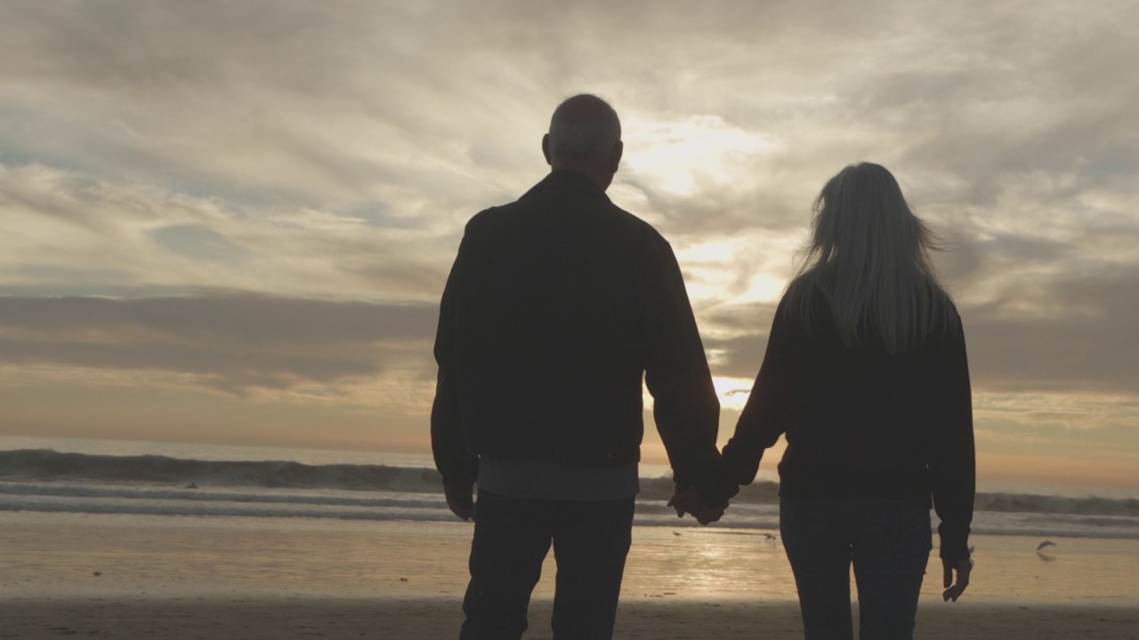 拉美老年夫妇在海滩上手牵着手视频下载