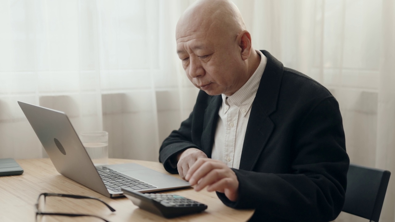 没有头发的亚裔中国高管在开放式办公室里用笔记本电脑打字视频素材