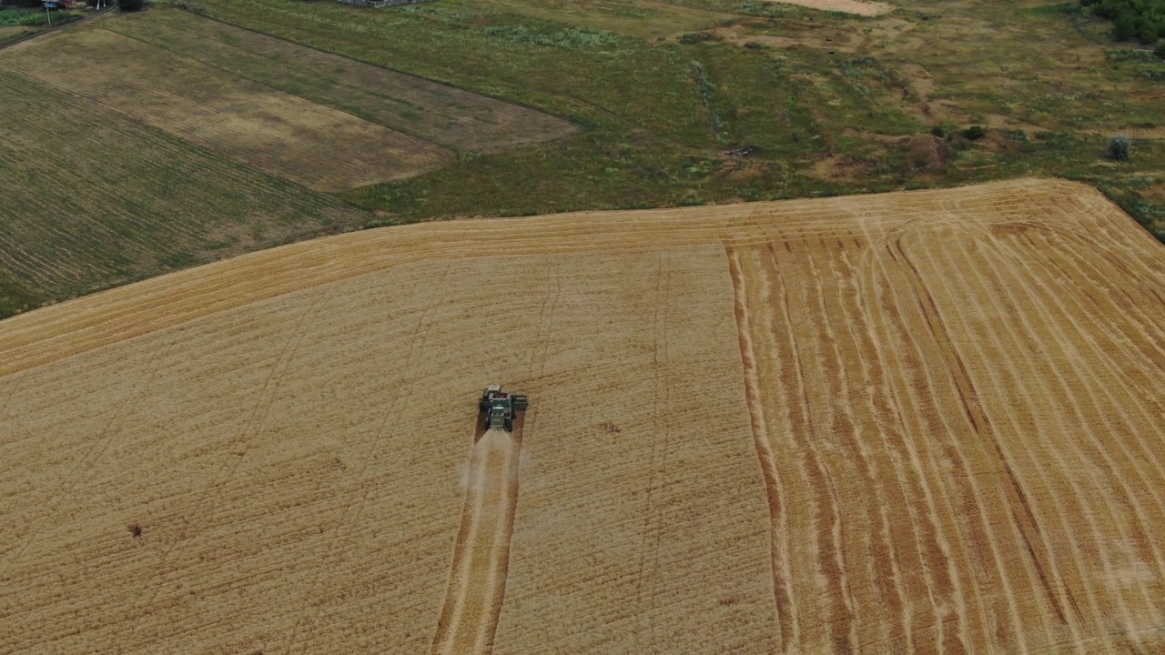 乌克兰马里乌波尔田里的联合收割机的航拍照片。在麦田里工作的收割机。联合农机收获金黄成熟的麦田。视频下载