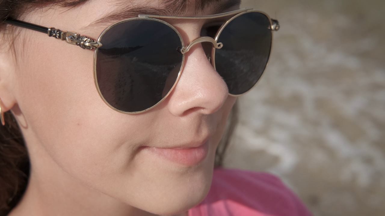 戴着太阳镜坐在沙滩上。视频下载