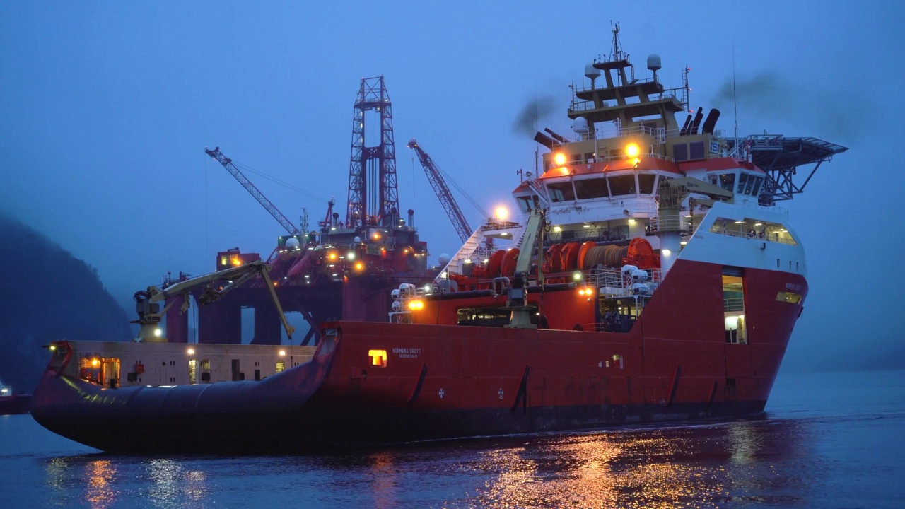 锚汉德勒在挪威峡湾，背景是一个石油平台。视频素材