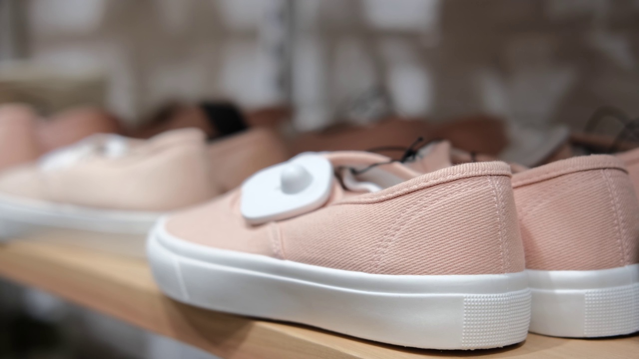 木制货架上陈列着各种尺寸的白色橡胶底、精致的粉红色夏季鞋。鞋子是从侧面展示的视频素材