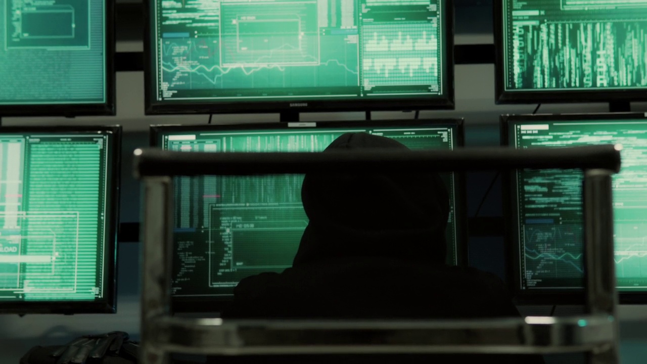 一名黑客程序员穿着连帽衫，戴着黑色黑客面具，隐藏自己的身份，利用电脑进行黑客活动视频素材