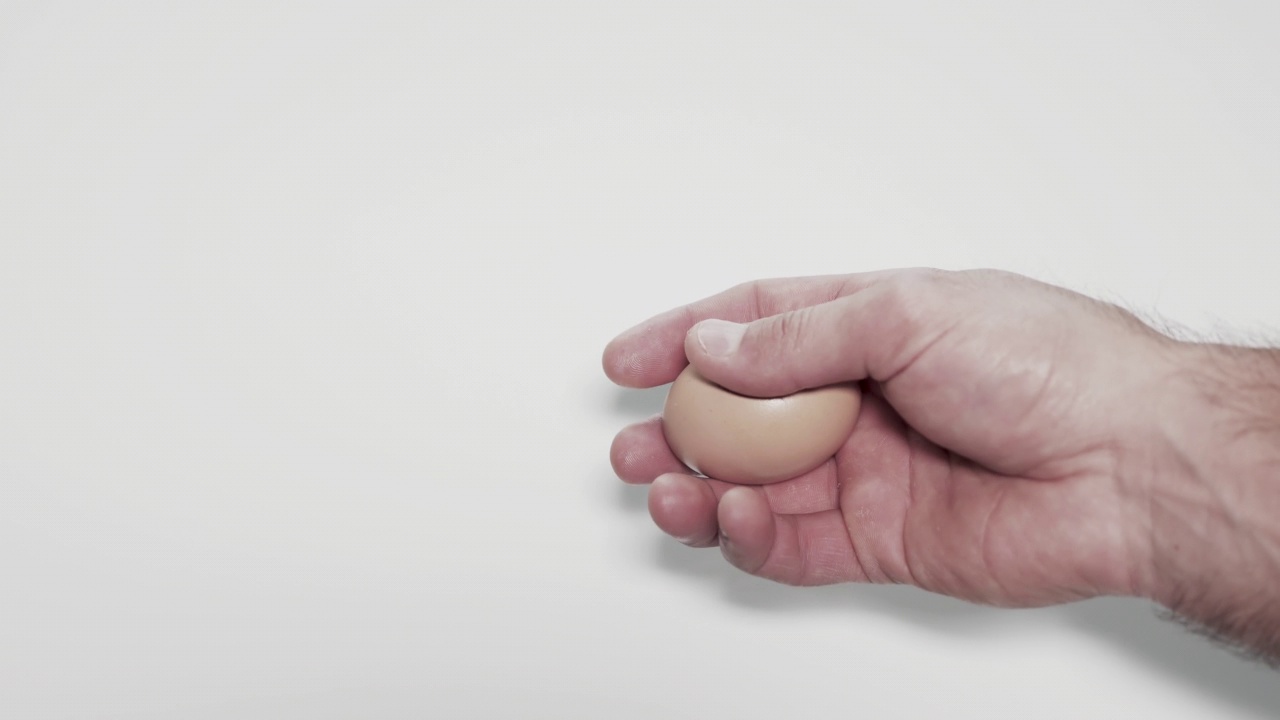 手里拿着鸡蛋。鸡蛋在人的手中，白色的背景。把鸡蛋。视频下载
