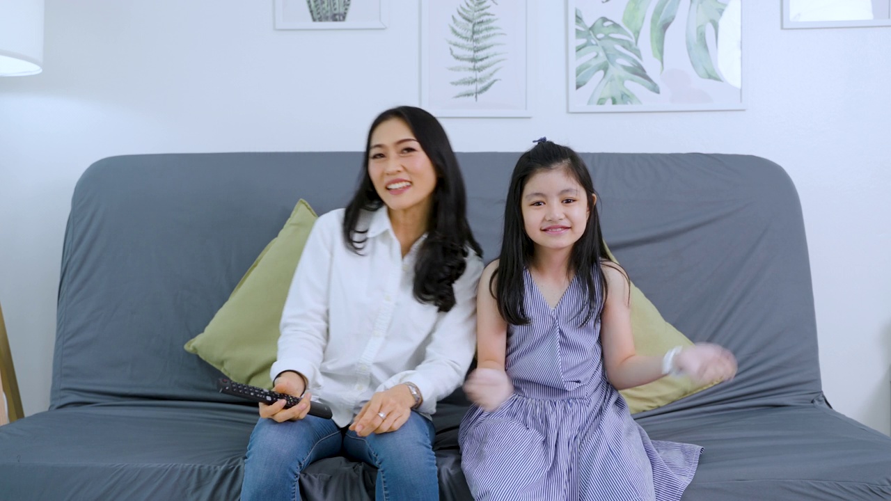 亚洲家庭坐在沙发上一边看电视一边跳舞视频下载