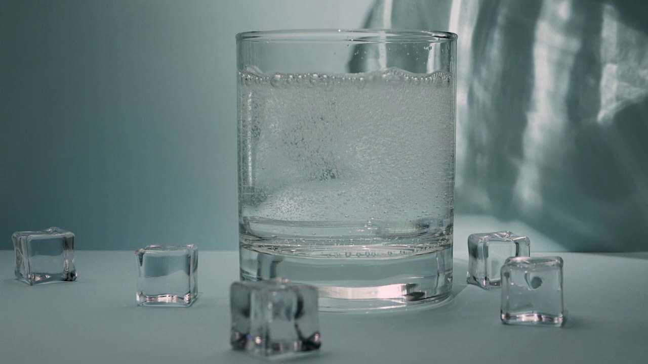 将饮用水、带有晶体的矿泉水倒入玻璃杯中视频素材
