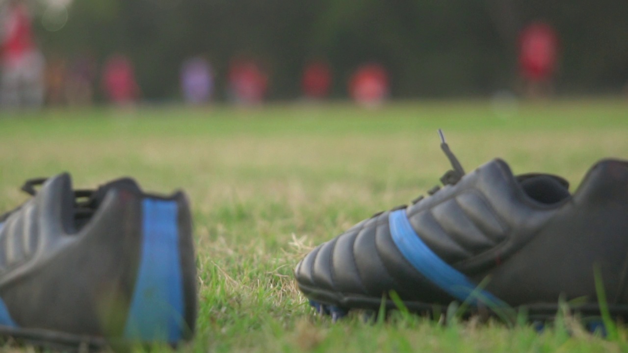 运动鞋在球场上与足球运动员练习的背景。视频素材