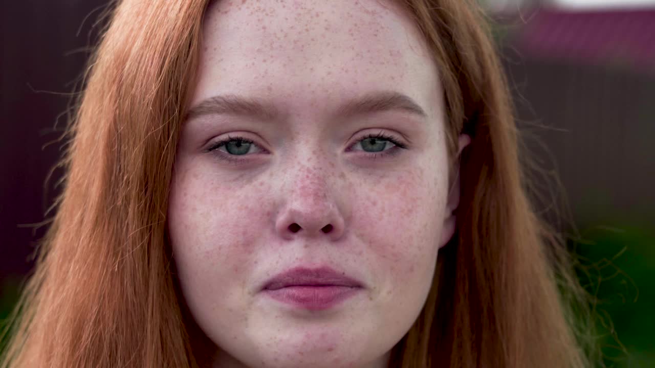 18岁的红头发女孩悲伤地看着镜头，擦着眼泪。特写镜头视频素材