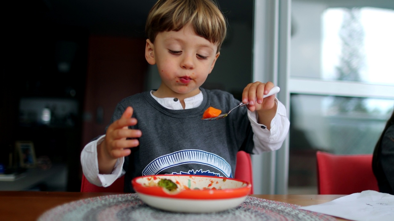 一个快乐的小男孩独自吃着健康的午餐视频素材
