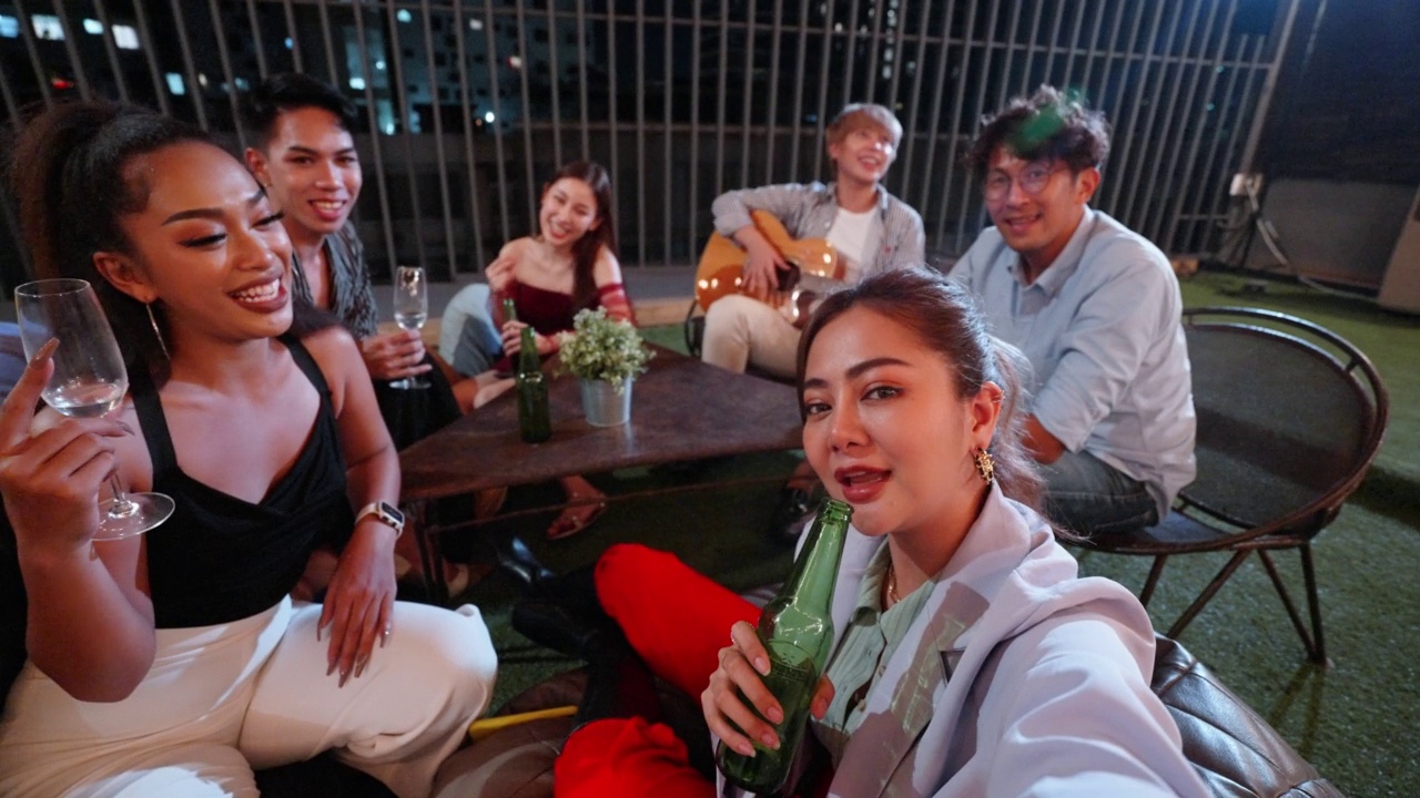 一群多元化的亚洲朋友喜欢一起唱歌，晚上用手机自拍视频下载