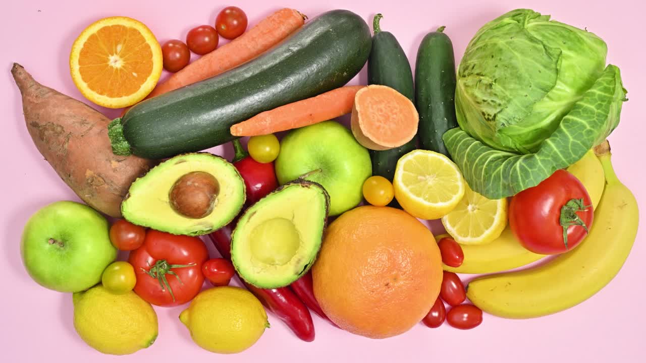成熟的有机水果和蔬菜的创意定格动画使框架上粉彩粉色的背景。平躺视频下载