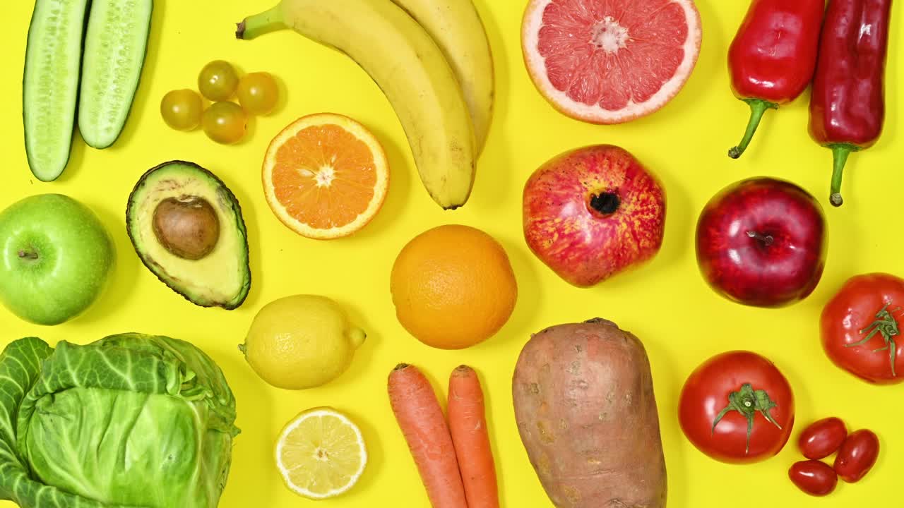 有机健康的水果和蔬菜在鲜艳的颜色移动在黄色的背景。食物的模式。停动平铺视频下载