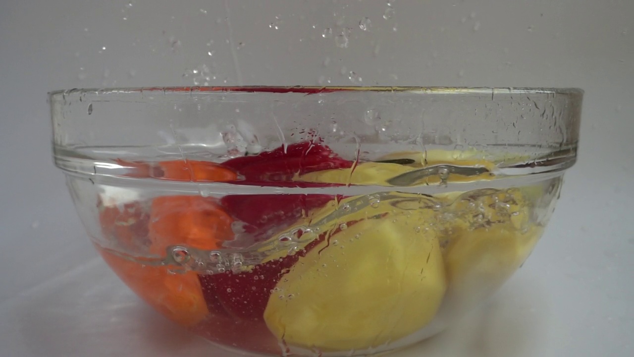 菜汤落集，土豆、胡萝卜、洋葱、西红柿、甜椒在玻璃碗里加水。缓慢的运动。视频素材
