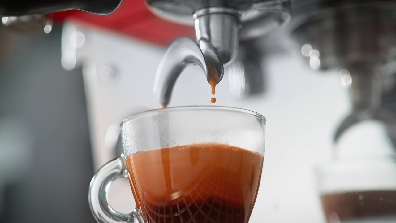 咖啡从浓缩咖啡机的过滤器滴到透明的杯子视频素材