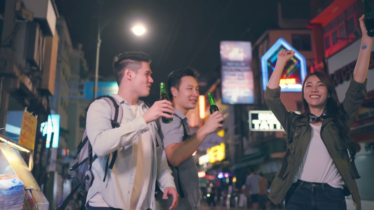 一群亚洲人在一起喝酒、喝酒、开派对。年轻的男人和女人在城市旅游旅游，在假期一起在黑暗的夜晚拿着啤酒在路上。视频素材