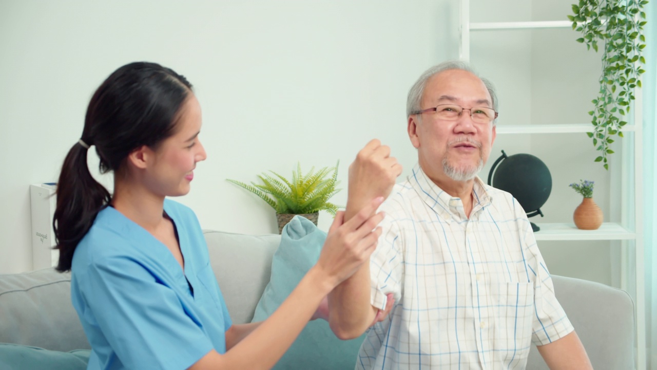 亚洲女性物理治疗师检查老年男性患者的手臂运动。护士在家中客厅沙发上协助对老年男性患者手臂进行物理治疗。视频下载